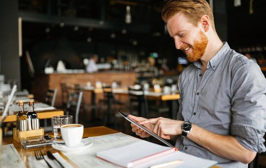 man die kijkt naar een iPad in een restaurant