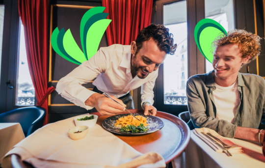 User in Restaurant mit Kellner, der Parmesan auf das Teller reibt