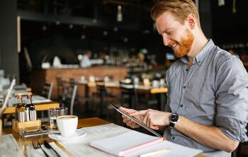 ein Mann schaut in einem Restaurant auf ein iPad