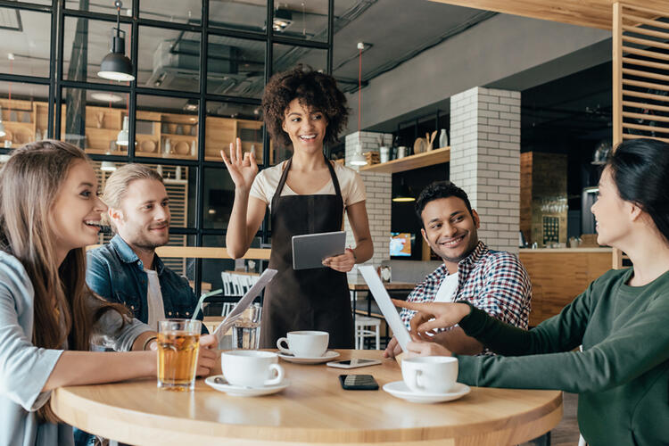 Kellnerin begrüßt Kunden - Restaurantmanagement