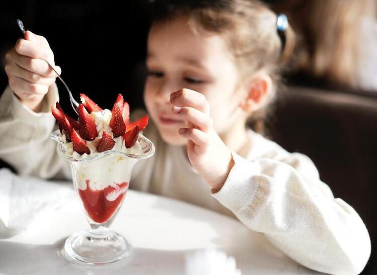 Bambino che mangia un gelato alla fragola