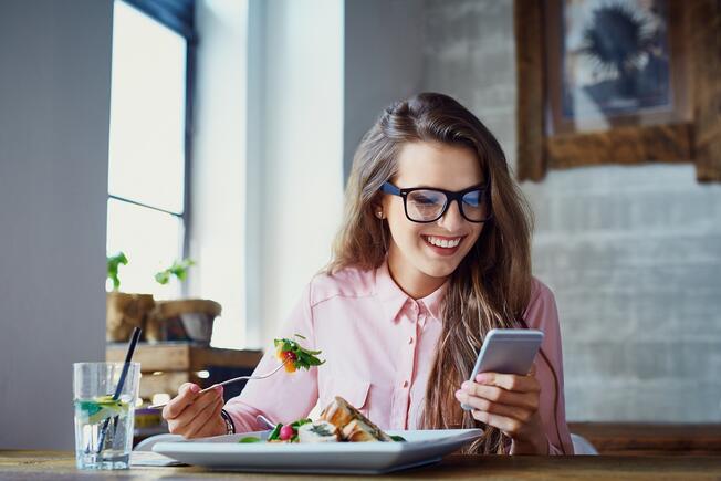 Woman with phone eating salad
